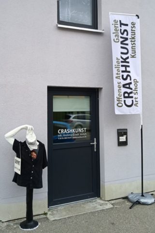 Ansicht vom Eingang in das Atelier und Galerie in Kempten mit Crashkunst Flagge und Braineater-Skulptur